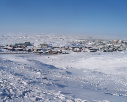 Snowy townscape under clear blue sky.