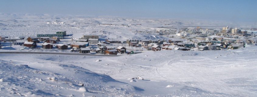 Snowy townscape under clear blue sky.