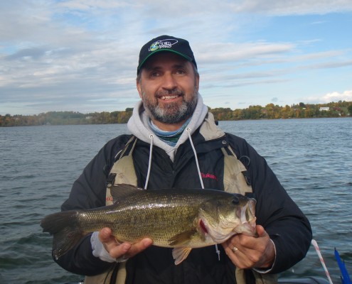 Man proudly holding a large fish by the water.