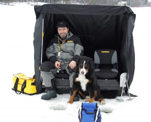 A child in winter gear sitting on a bench with a dog and toys.
