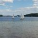 Sailboats on a lake under cloudy sky.