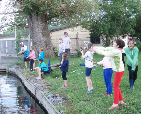 Children playing and balancing on a narrow stone edge by water.