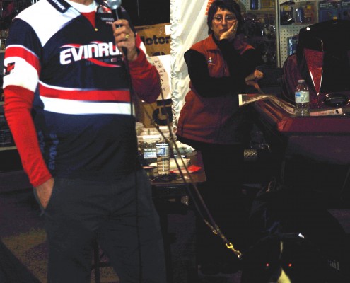 Two people posing in a room with gaming equipment and a TV.