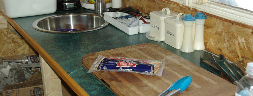 A cluttered kitchen countertop with utensils and food items.