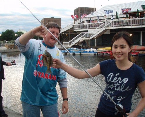 Two people happily holding a long, thin squid by the seaside.