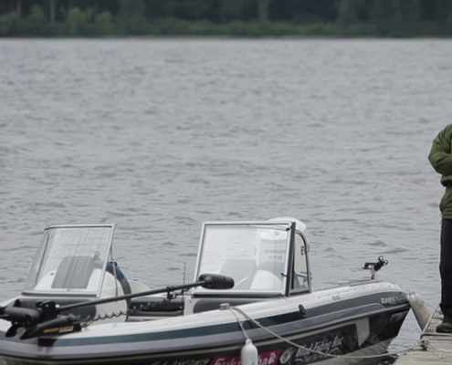 A motorboat on calm water near a forested shoreline.