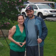 A couple smiling outdoors with cars in the background.
