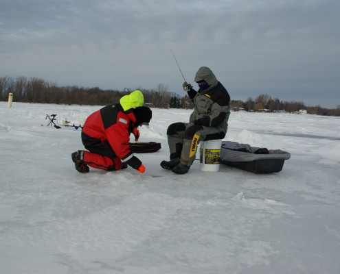 People setting up equipment on ice for fishing or research.