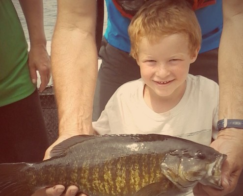 Young boy proudly holding a large fish he caught.