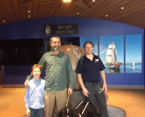 Three people posing inside a modern building lobby.