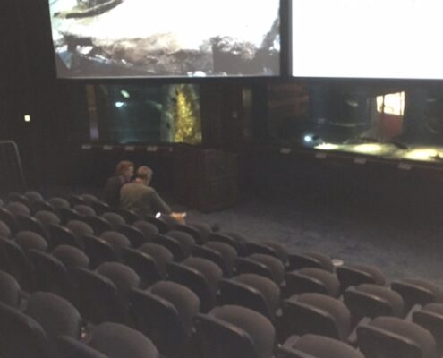 Empty auditorium with rows of seats and a stage.