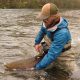 Person releasing a fish into a river.
