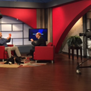 Two women engaged in a television interview on a vibrant studio set.