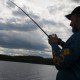 Person fishing on a lake during cloudy weather.