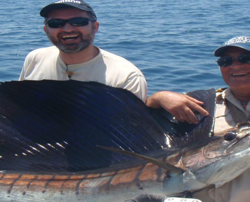 Man proudly holding a large fish he caught at sea.