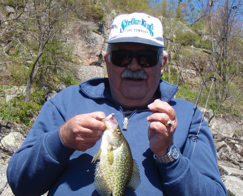 Angler proudly displays a freshly caught fish outdoors.