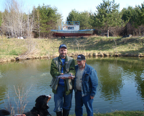 Two people posing by a pond in an outdoor park.