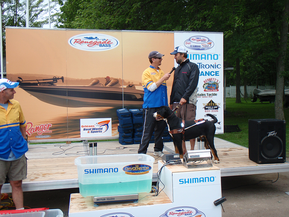 Winners celebrate on the podium at a sporting event with trophies and prizes.