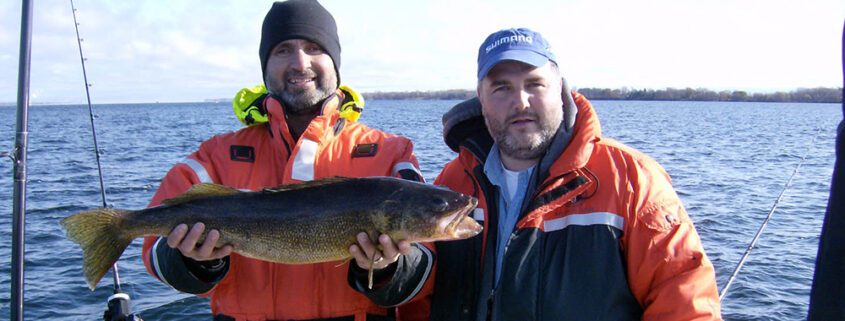 Two men in outdoor gear holding a large fish, smiling.