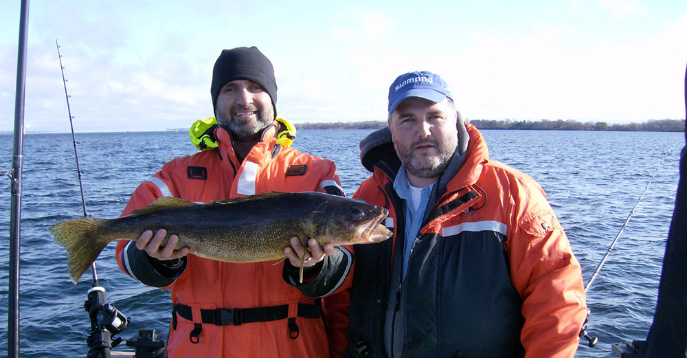 Two men in outdoor gear holding a large fish, smiling.