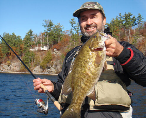 Man proudly holding a freshly caught fish outdoors.
