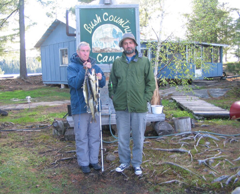 Two people in casual outdoor clothing stand in a backyard garden area.