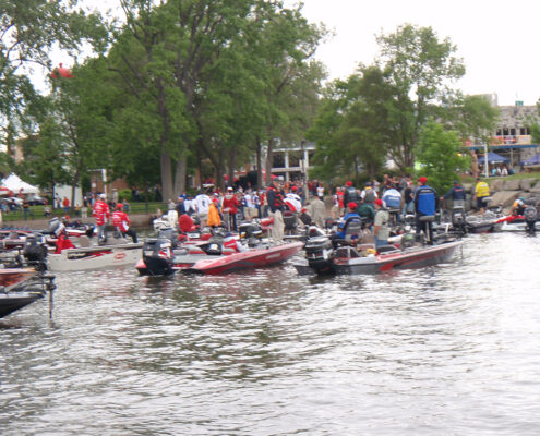 Crowded boats filled with people enjoying a water parade.