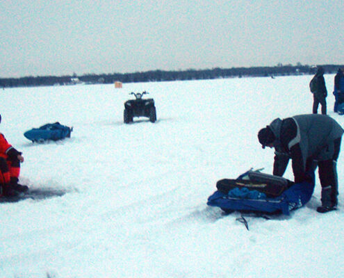People preparing or skiing on a snowy landscape with snowmobiles.