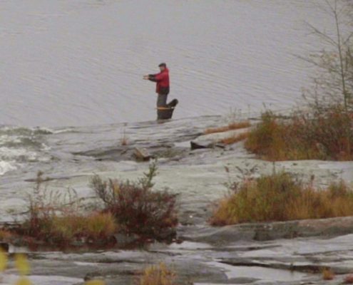 A person walking on a snow-covered landscape with patches of grass.