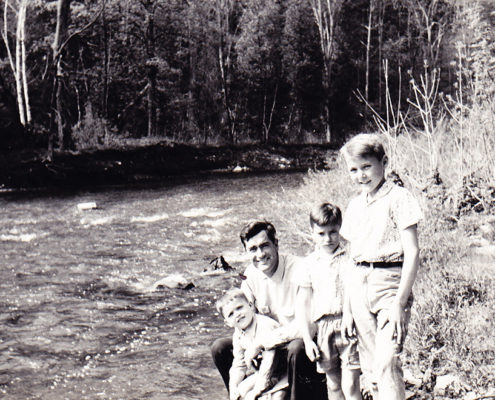 Photo of Dad holding Lawrence with Marc and Thomas standing on the shore