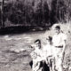Photo of Dad holding Lawrence with Marc and Thomas standing on the shore