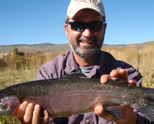 Smiling fisherman holding a big rainbow trout
