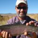 Smiling fisherman holding a big rainbow trout