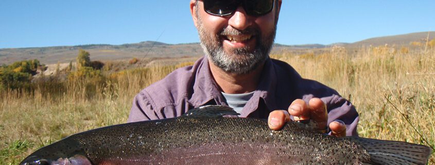 Smiling fisherman holding a big rainbow trout