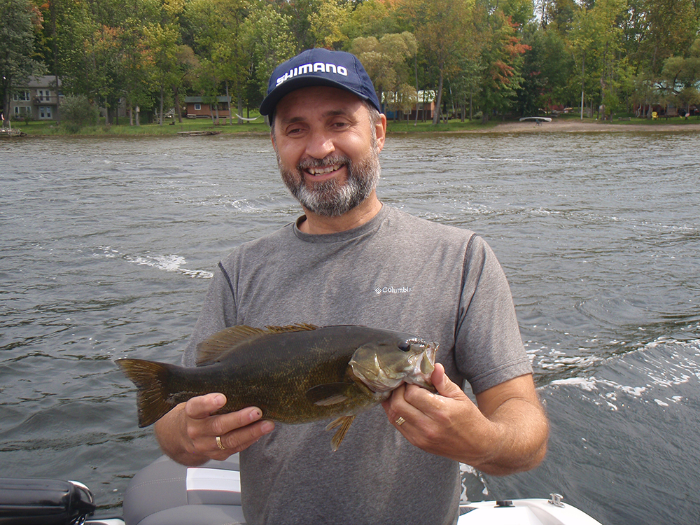 Man holding a large fish by a river.