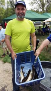 A person in a bright yellow shirt holding a blue basket outdoors.