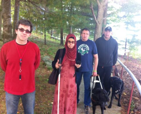 Group of friends posing outdoors with a dog on a sunny day.