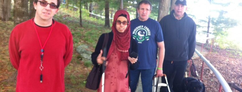 Group of friends posing outdoors with a dog on a sunny day.