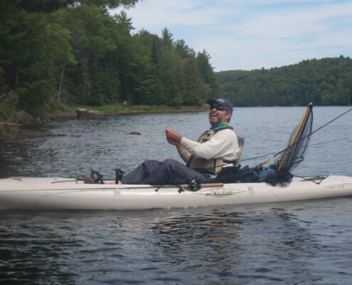 A person balancing on a log floating in a river.