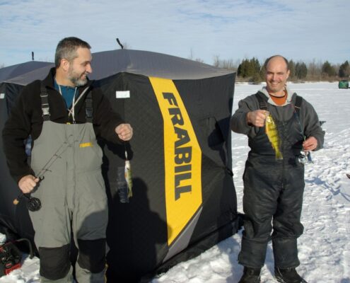 Two men holding a large yellow and black fish on a boat.