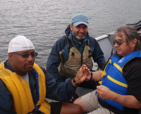 Three men in colorful attire sharing a joyful moment near water.