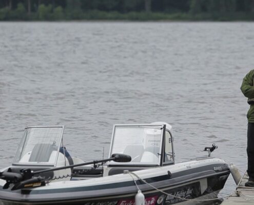 Two boats docked side by side on calm water under cloudy skies.