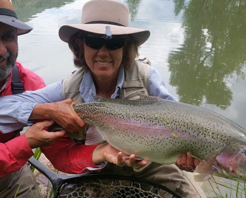 Two people holding a large fish outdoors.