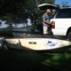 Man with small boat trailer near SUV.