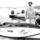Man with boat and dog on shore.